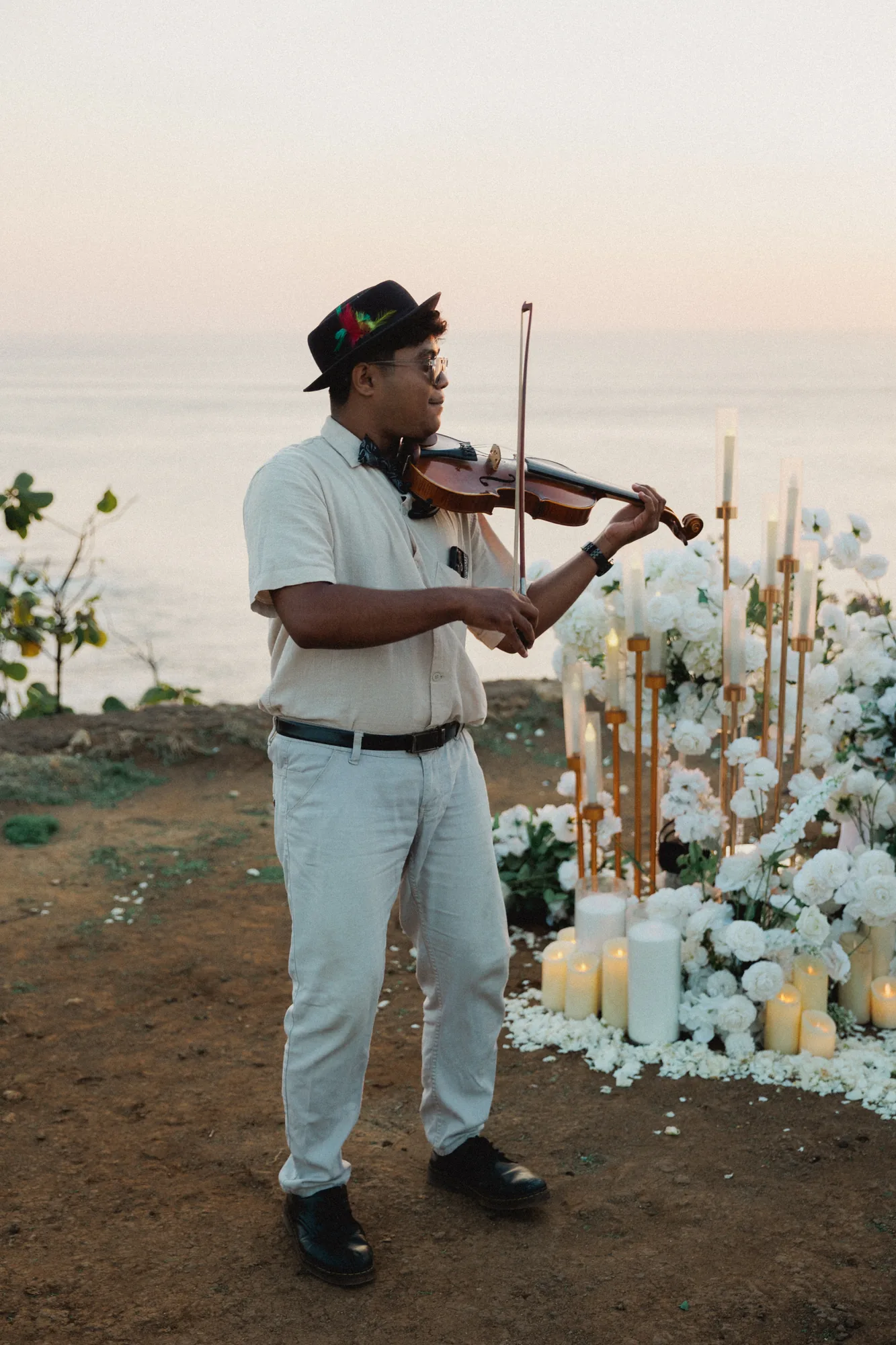 Violinist at a white floral clifftop proposal setup in Bali