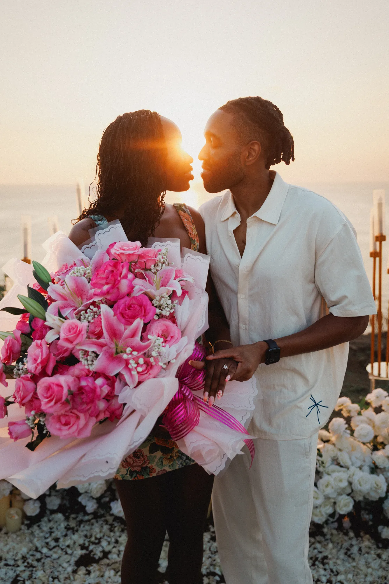 Couple with a pink bouquet at sunset at a Bali cliff proposal