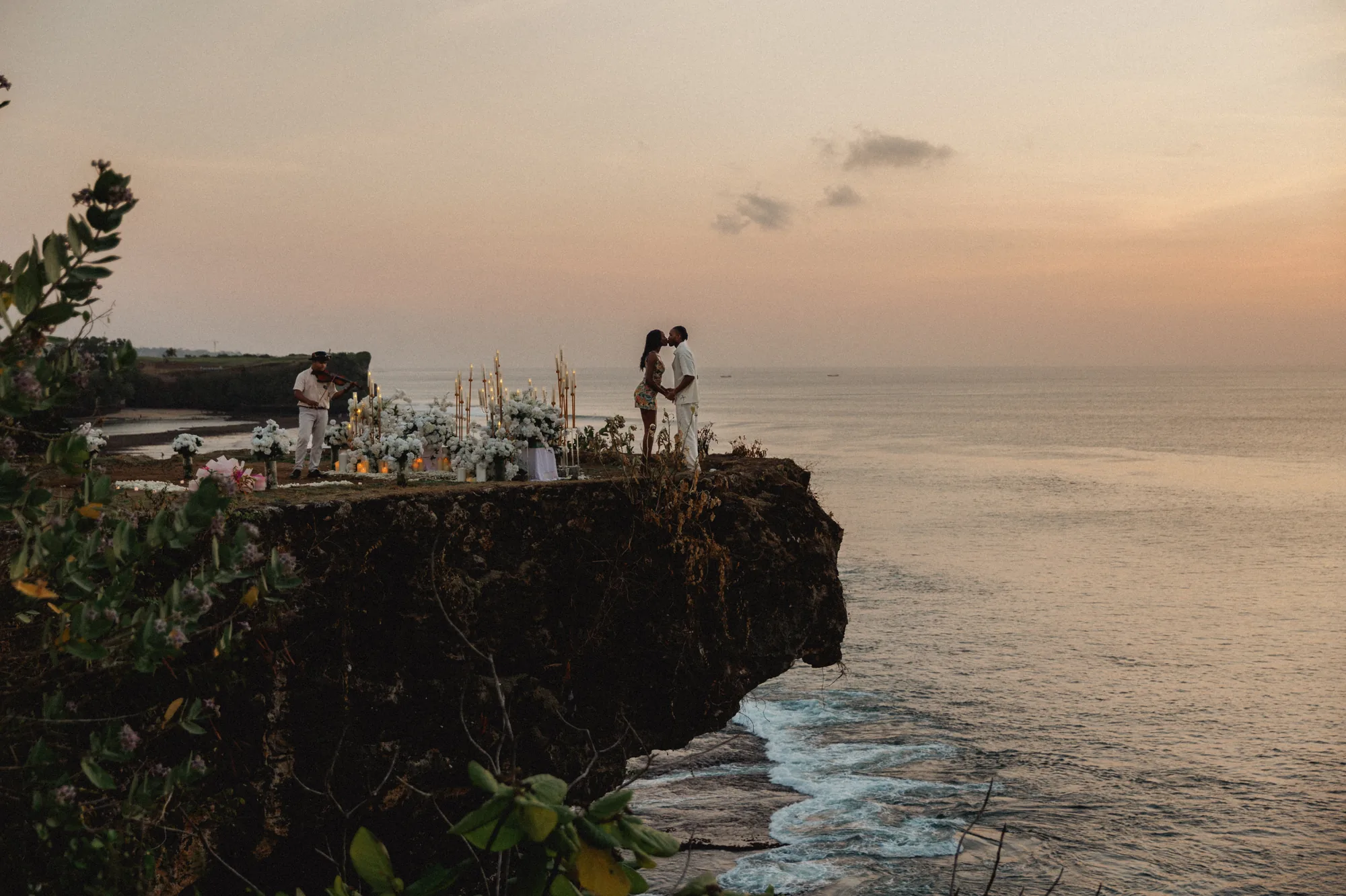 Couple on a clifftop at dusk above the ocean at a Bali proposal