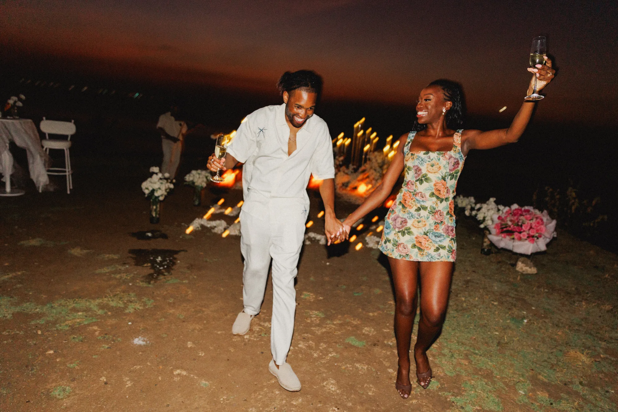 Newly engaged couple celebrating at night at a Bali cliff proposal