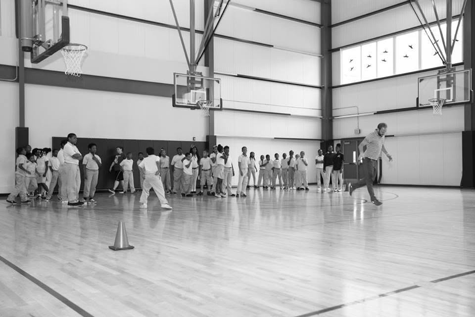Ty leaps across the gym floor as a line of students in school uniforms watches