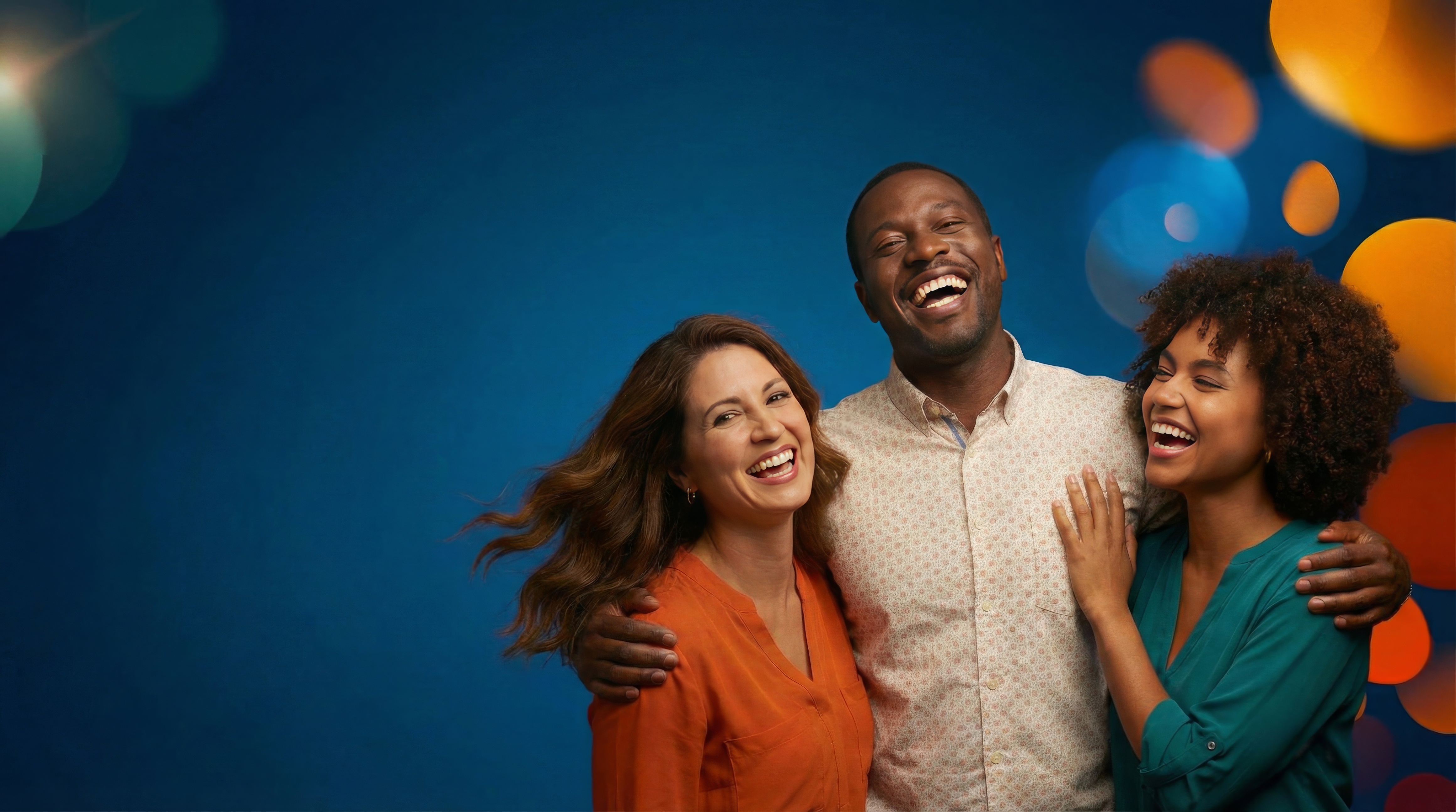 Three adults smiling and laughing together against a blue background with colorful blurred lights.