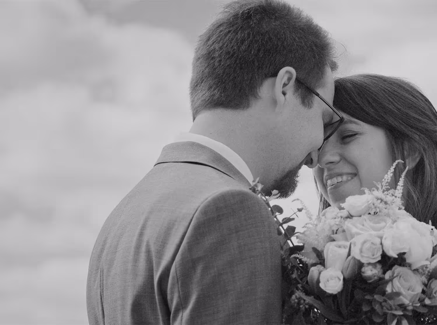 A married couple looking into each others eyes holding a bouquet of flowers
