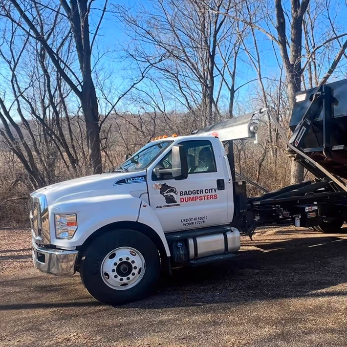 A dump truck branded with the Badger City Dumpsters logo