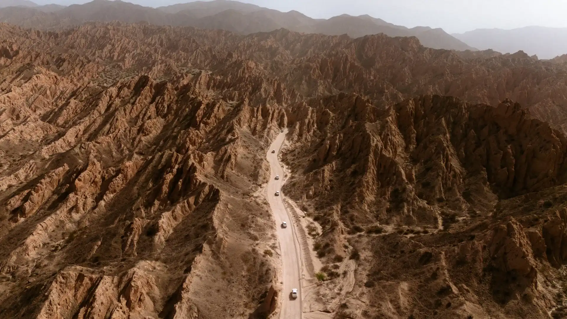 Car on a dusty road in the middle of rocky moutain