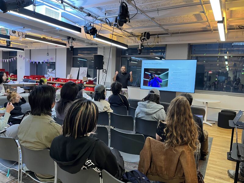 An image of shiv in a room of NYU students presenting a slide about handheld controls