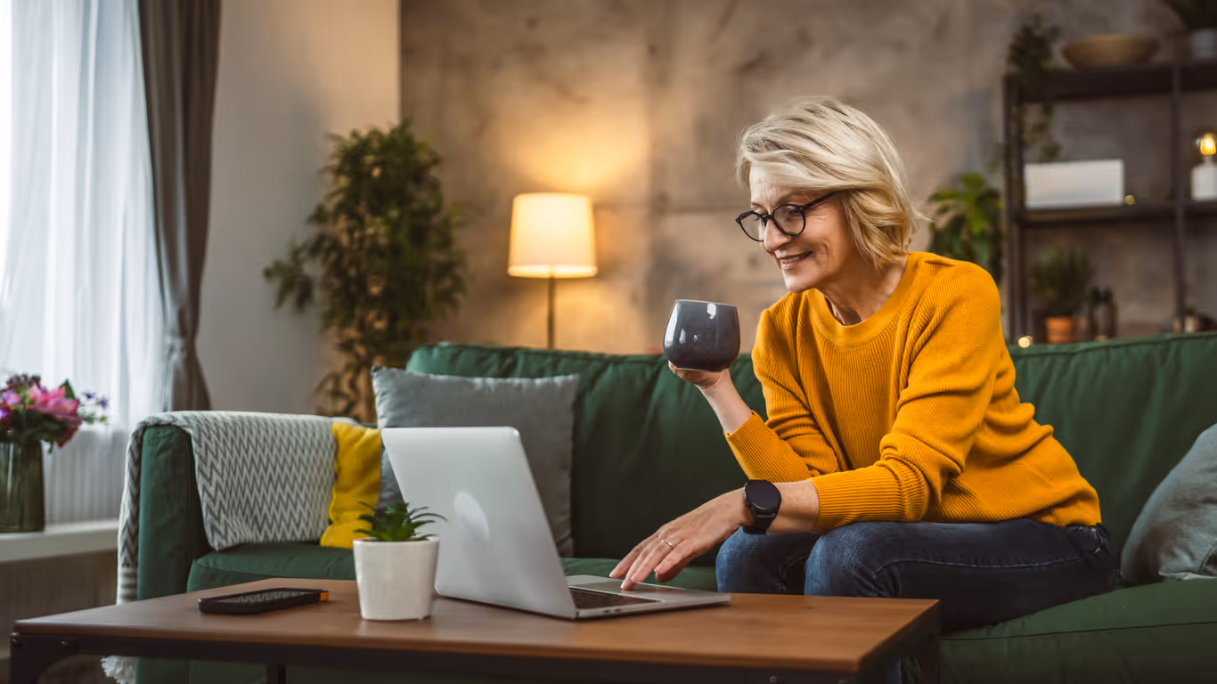A woman sitting on a couch holding a cup of coffee.
