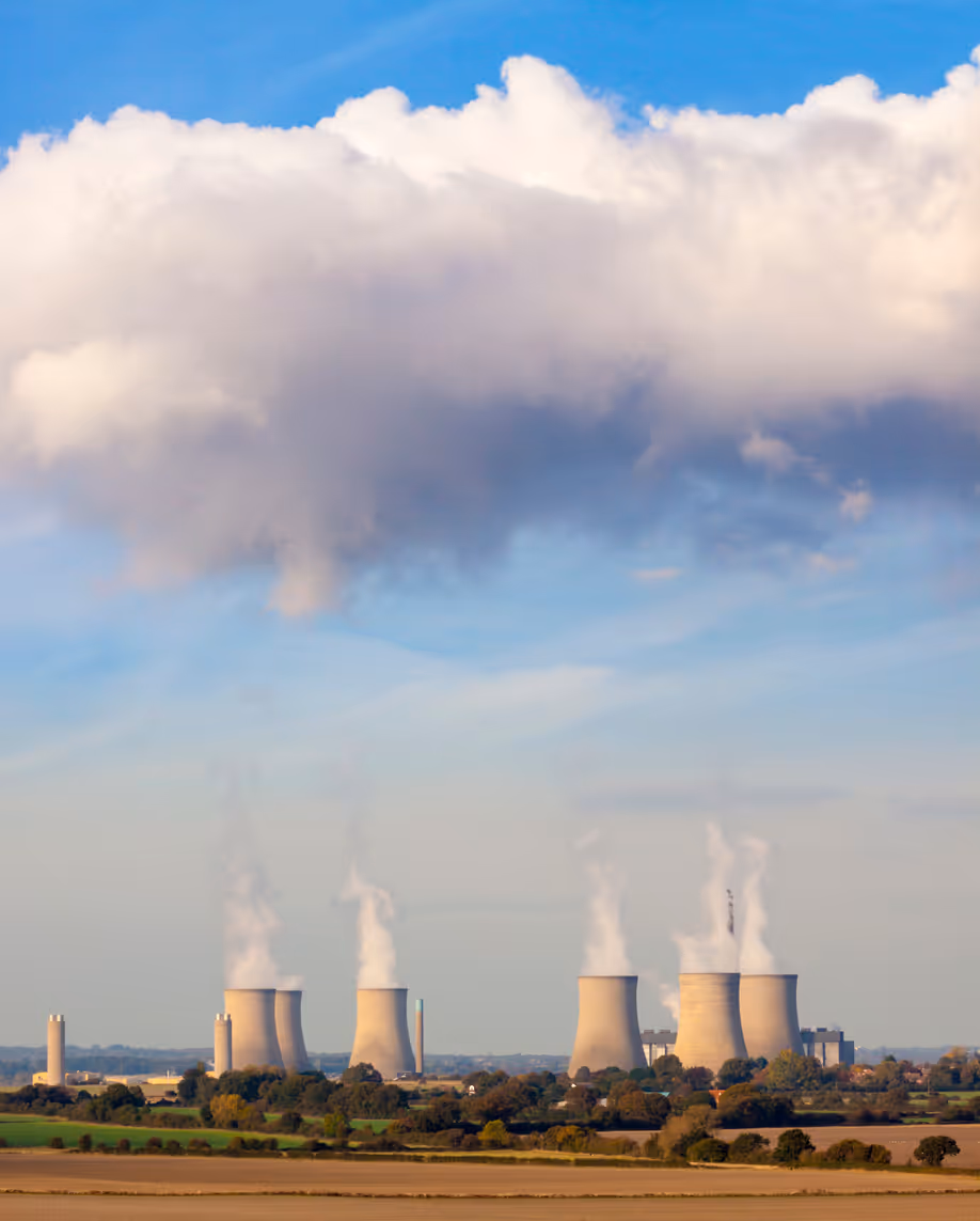 Power station cooling towers billowing out steam and smoke.