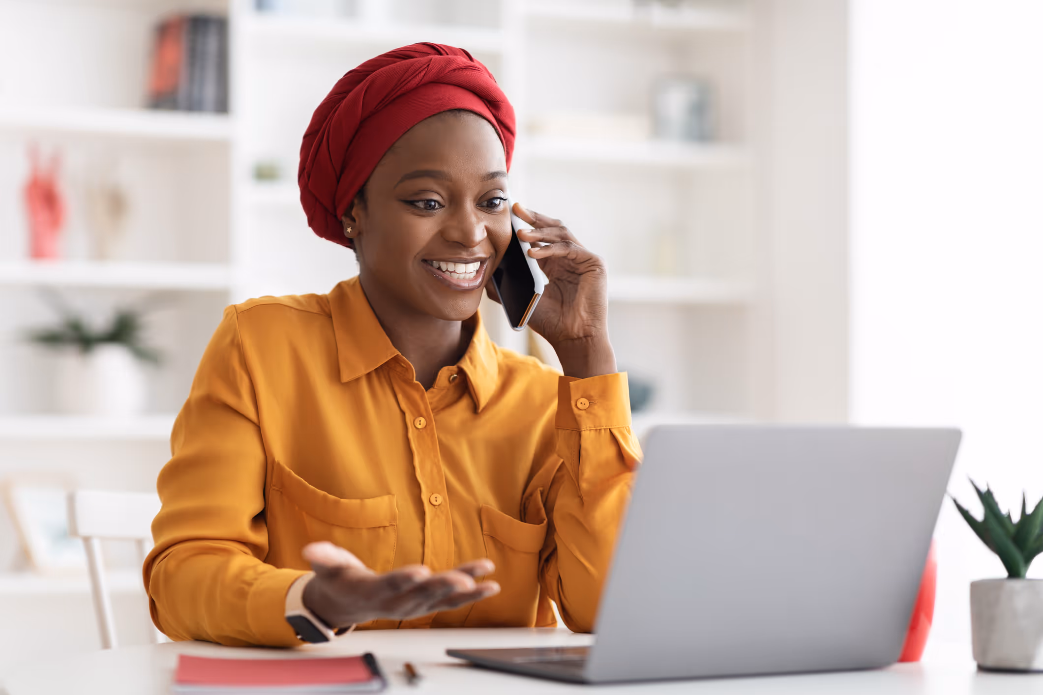 Woman on the phone while using a laptop.