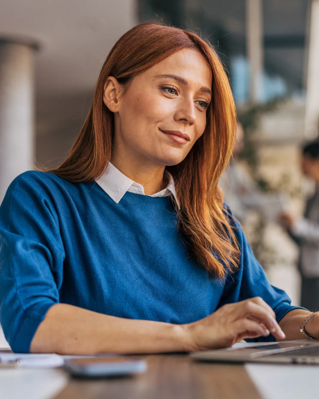 A woman smiling while looking at a laptop – an example of AideCRM’s approachable and inclusive brand photography style, reflecting its focus on empowering charity workers.