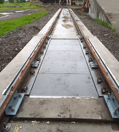 Close-up view of a railway track section with metal plates between the rails on a concrete base.
