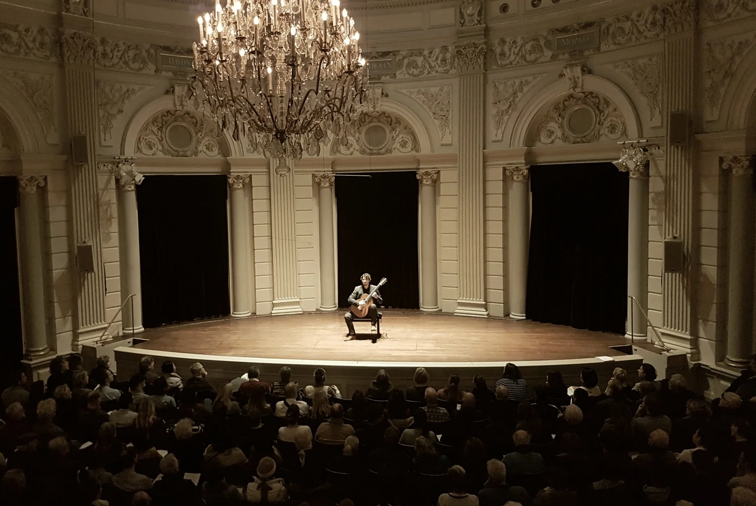 Silvan de Smit performing classical guitar on stage at the Concertgebouw in a sepia concert photo.