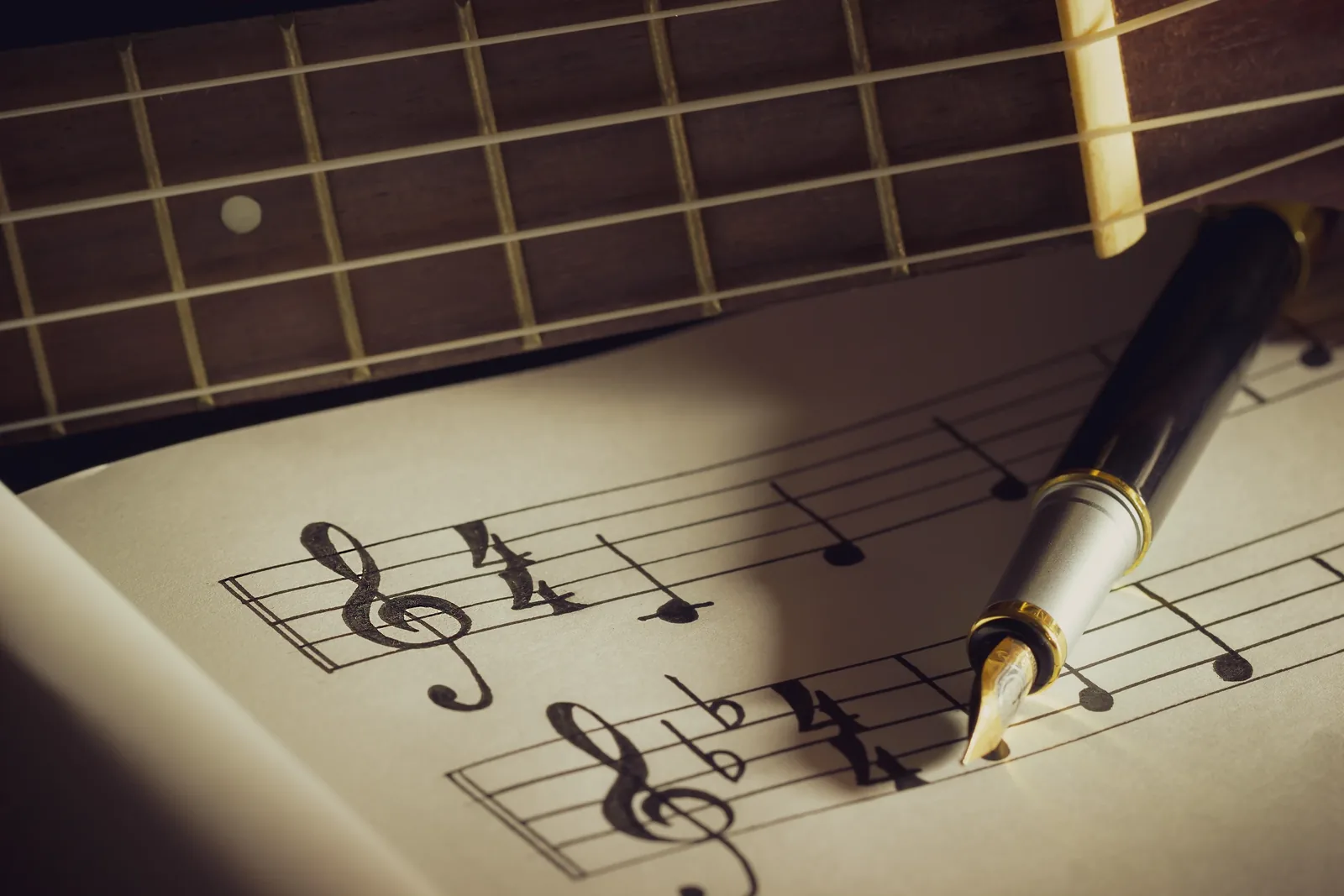 Close-up of classical guitar strings over sheet music for a Bach arrangement.