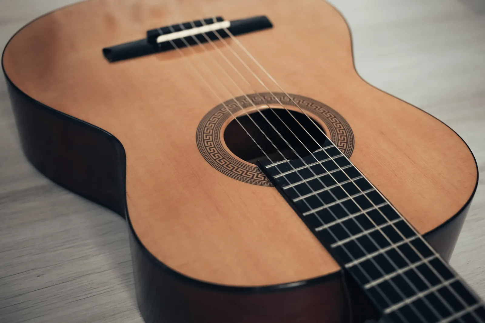 Close-up of classical guitar strings and wooden body.