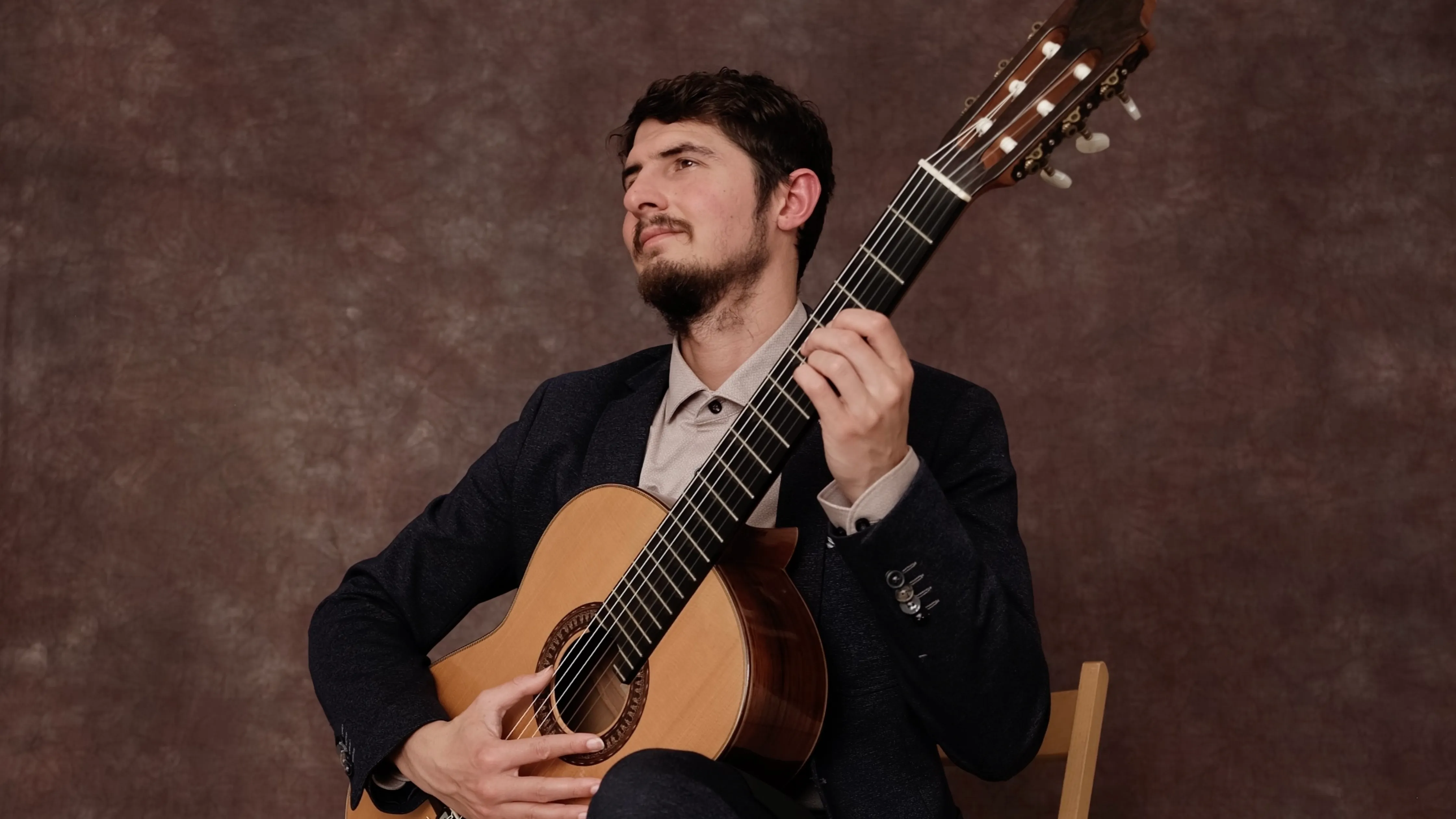Classical guitarist Silvan de Smit holding his guitar in a studio portrait.