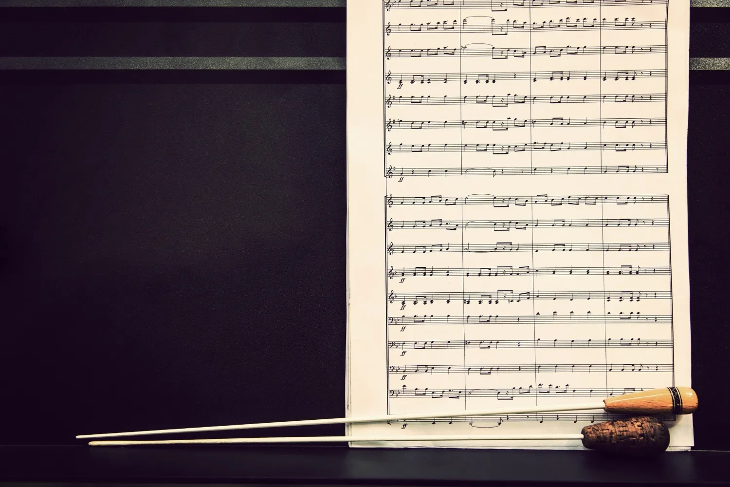A page of orchestral sheet music with conductor baton.