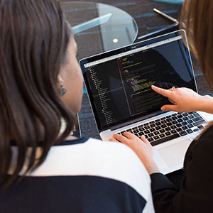 women discuss a project displayed on a laptop screen