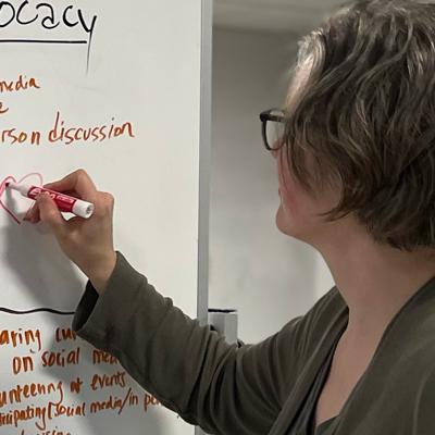brenda adds a heart to the advocacy portion of a journey map during a team brainstorming session