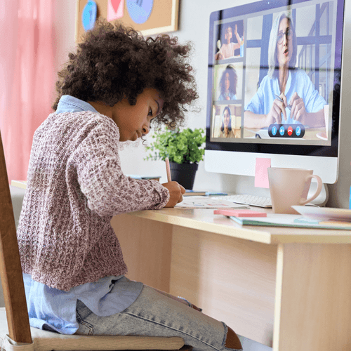 A girl writes on a piece of paper at a home desk