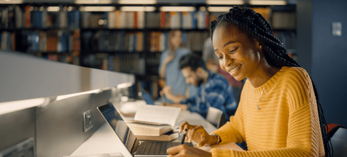 A student works on a laptop in a library