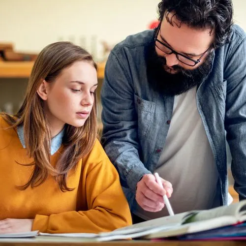 A student looks as her teacher shows her something on a notebook.