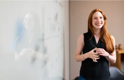 A woman stands at a whiteboard with a marker