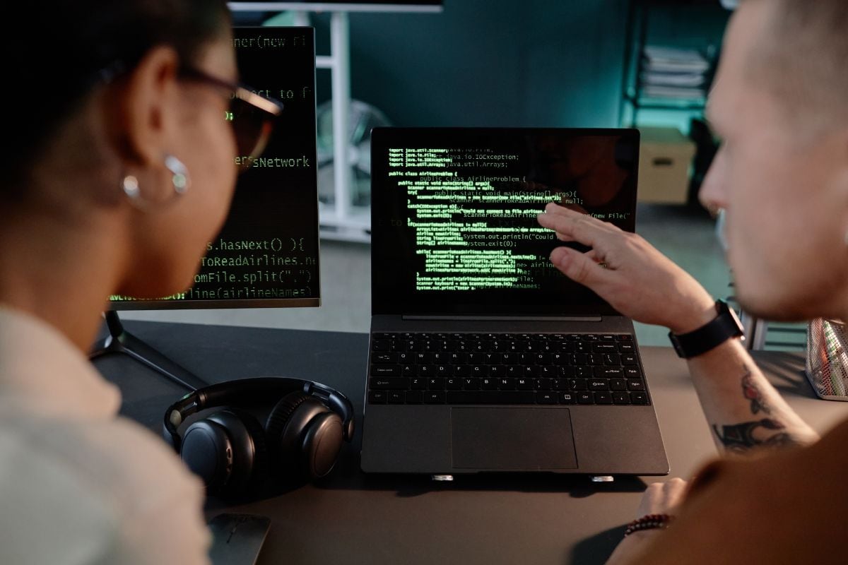 Two people coding on a laptop