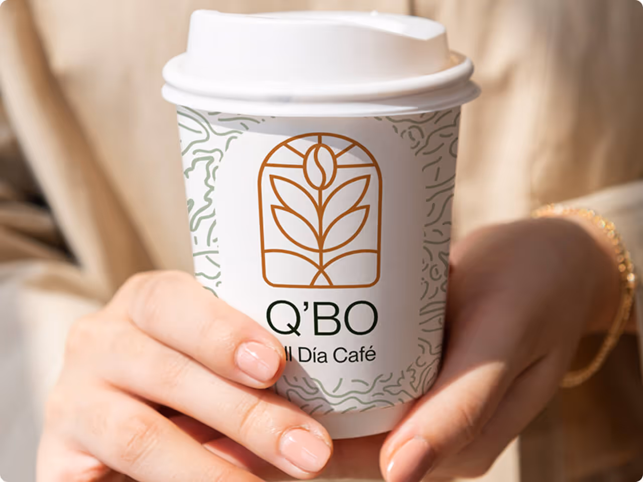 Hands holding a coffee package for Q’BO All Día Café