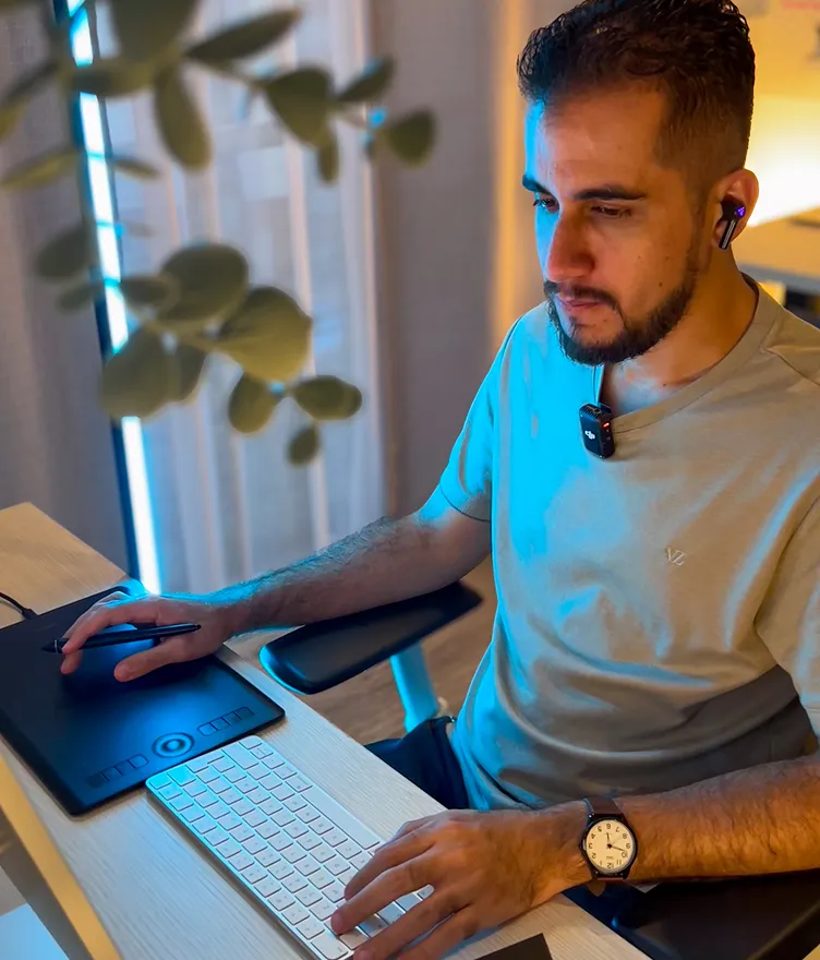 Juan Mac working at his design studio on a tablet and computer, focused on digital design workflow