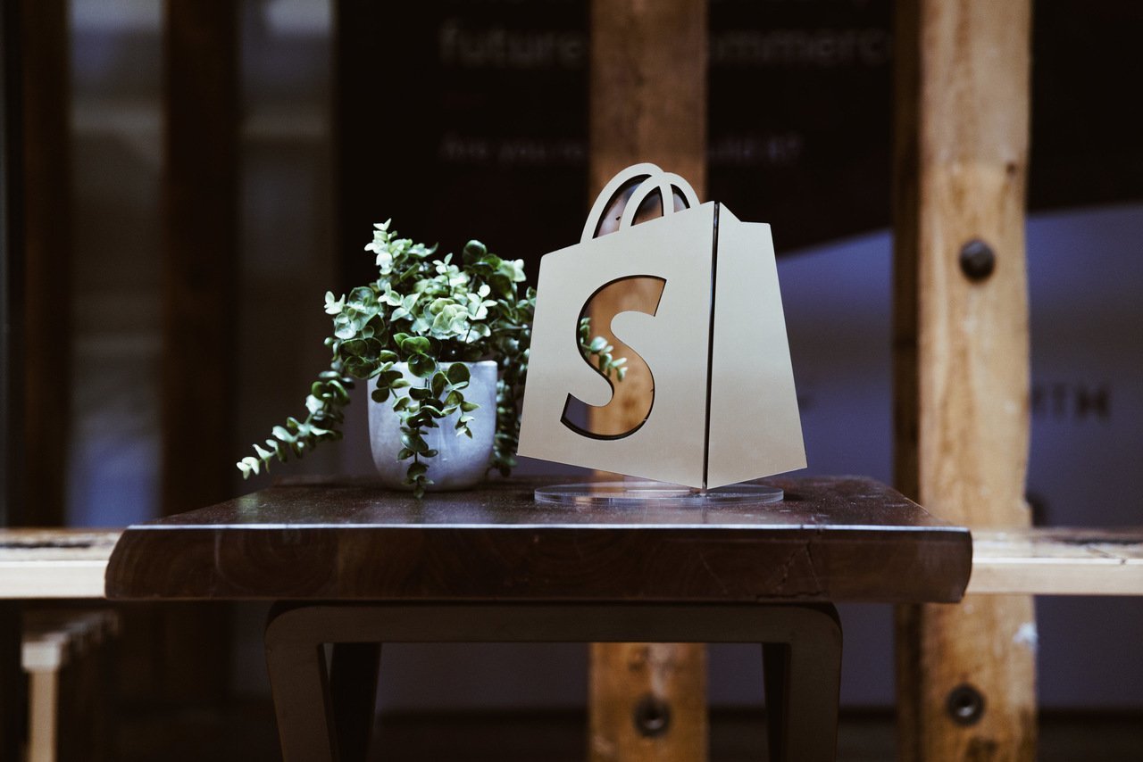 a shopify logo window with a plant next to it