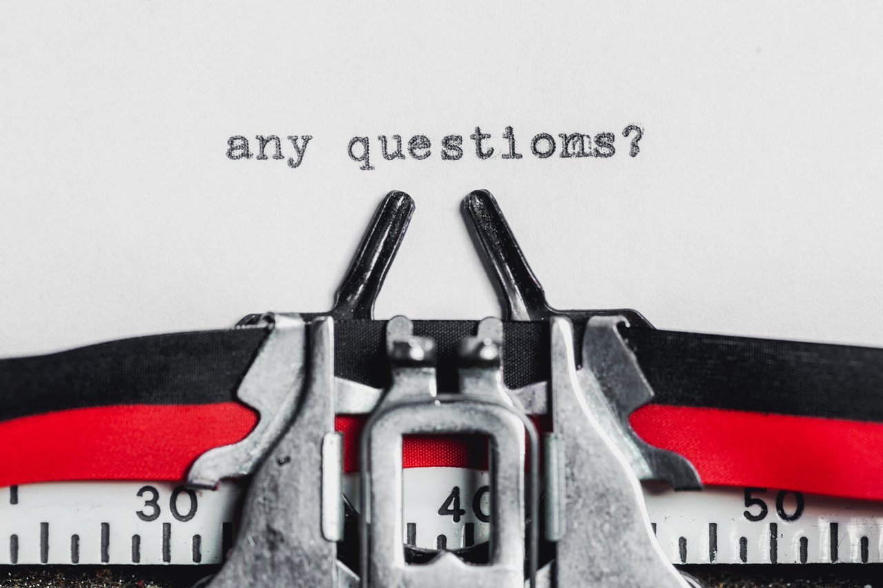 "any questions?" written on a paper on a typewriter machine