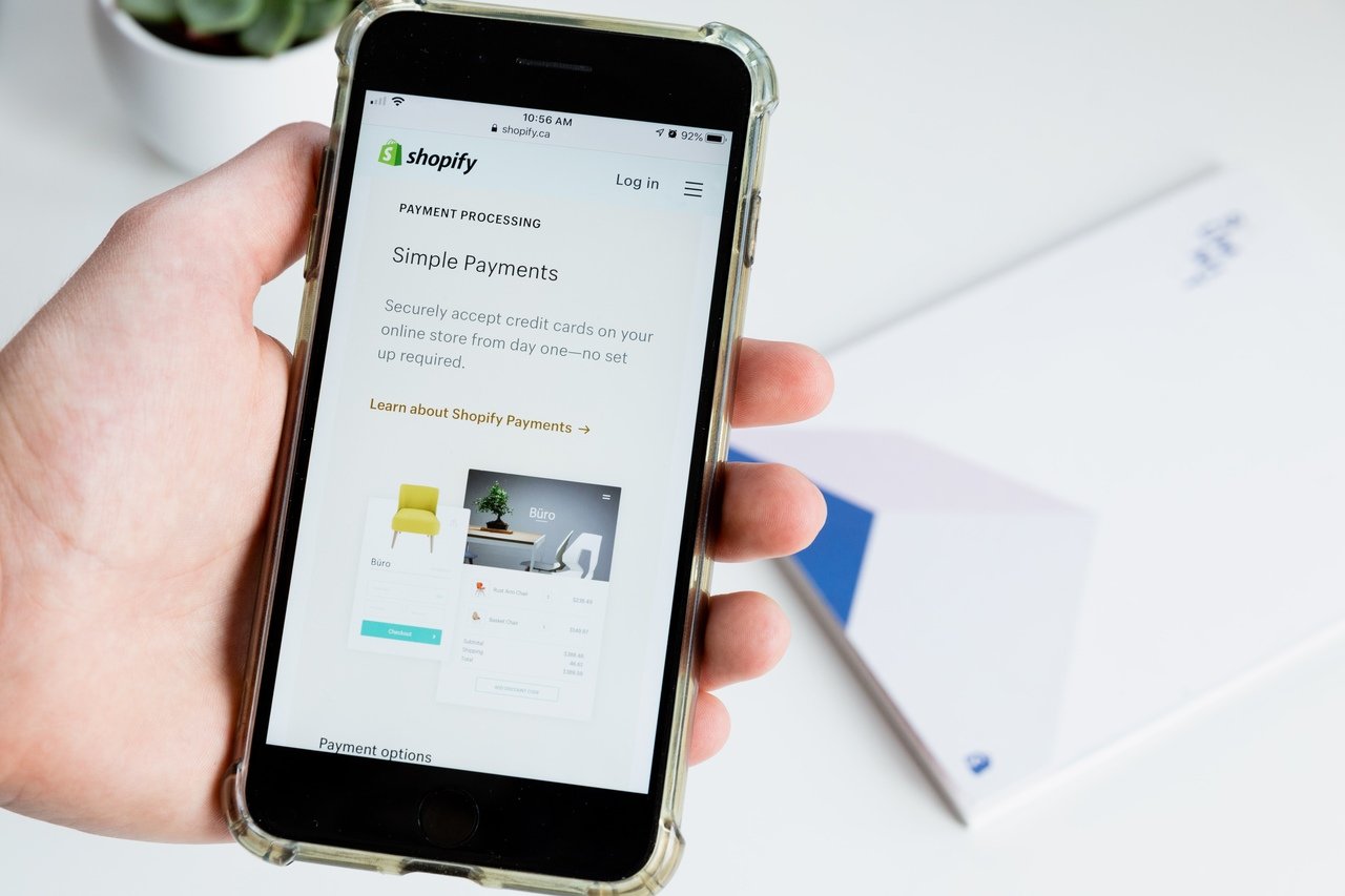 Bir Shopify mağazasının ödeme işleme sayfasını gösteren bir telefonu tutan el