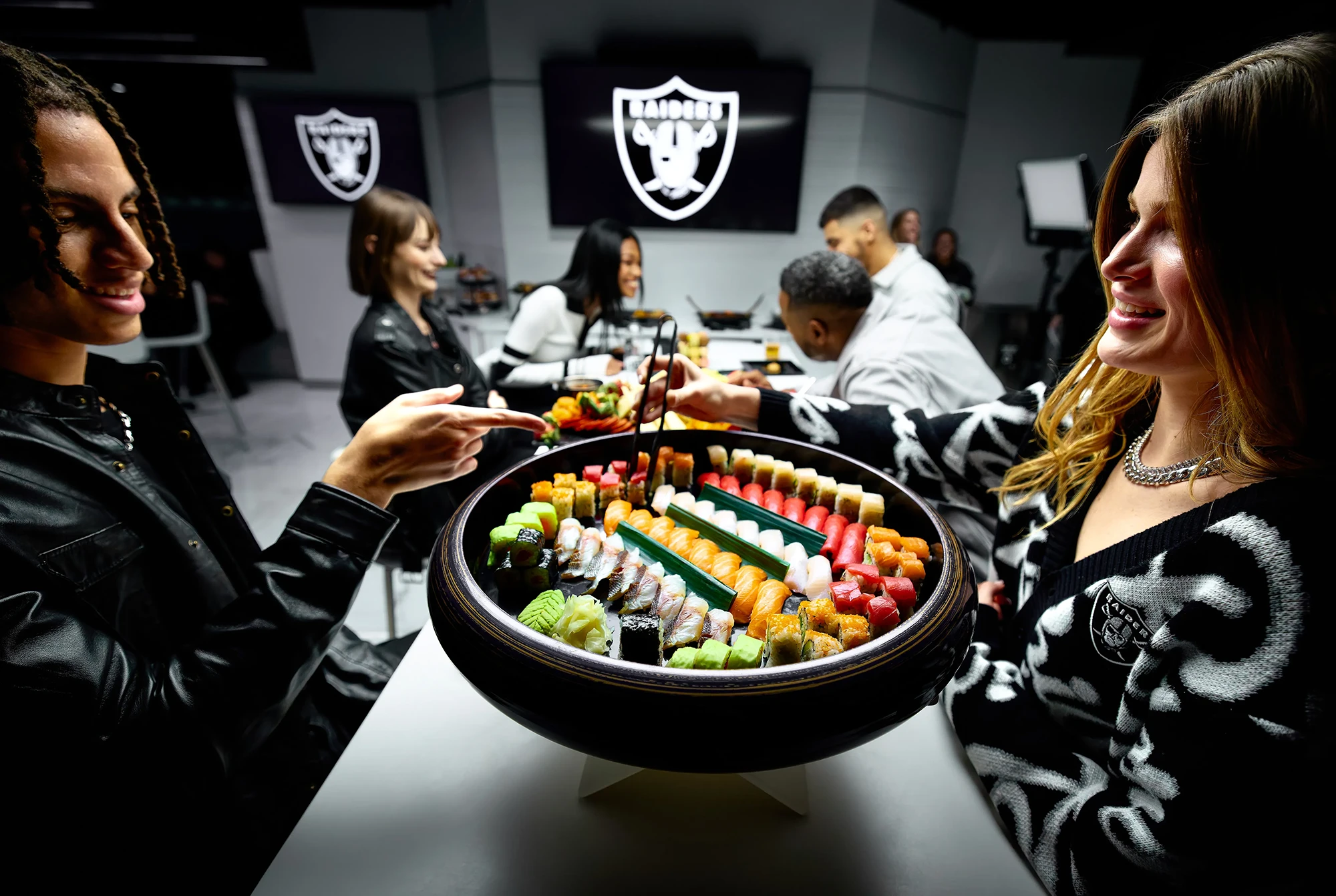 Buffet dessert station with cookies, chocolate cupcakes, small tarts, and bowls of toppings under warm lights.