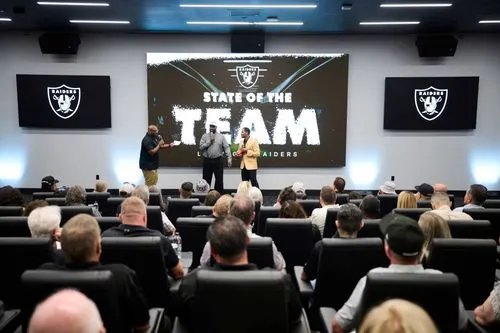 Two people wearing leis, standing on the football field at Allegiant Stadium.