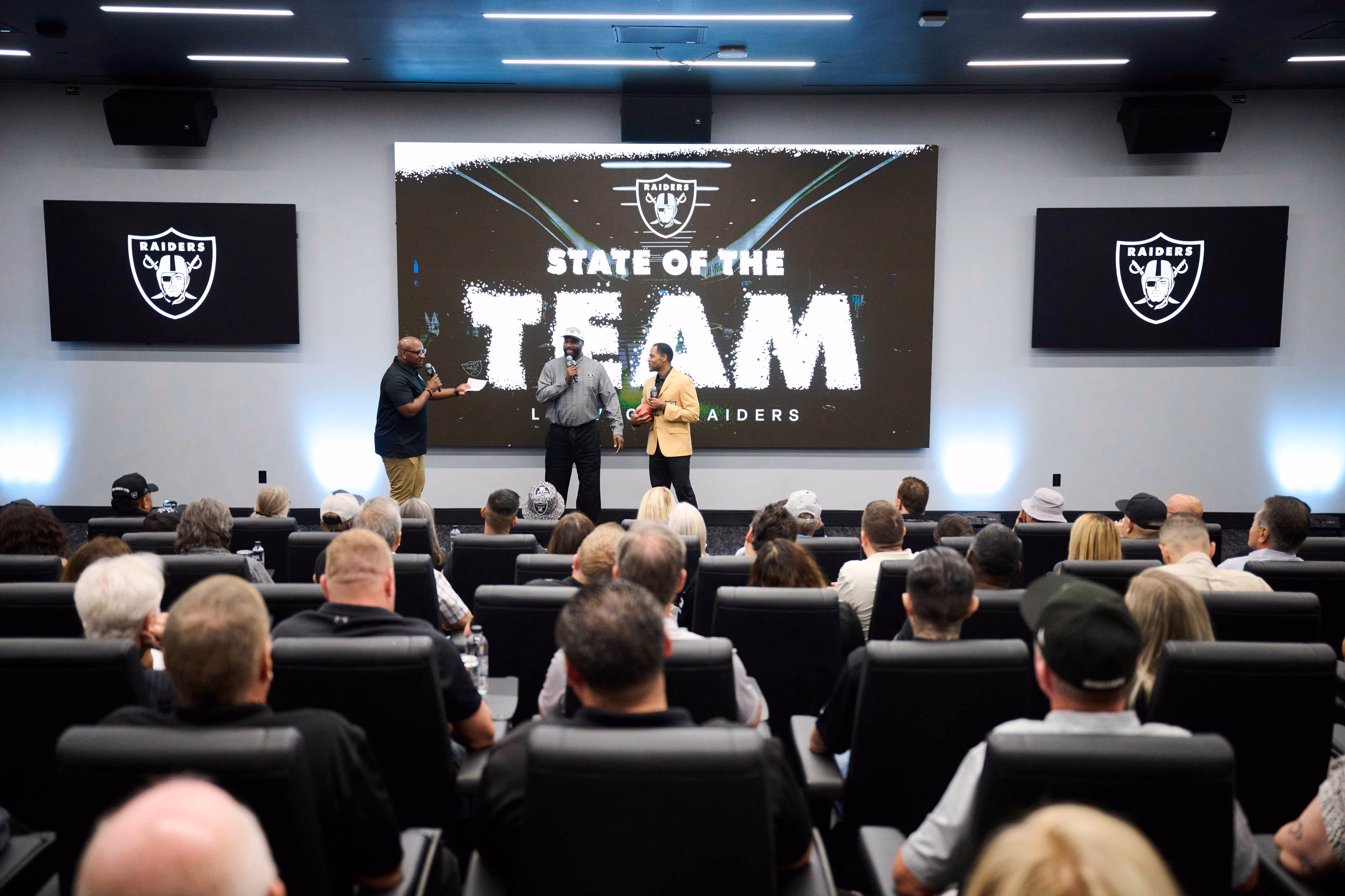 Two people wearing leis, standing on the football field at Allegiant Stadium.
