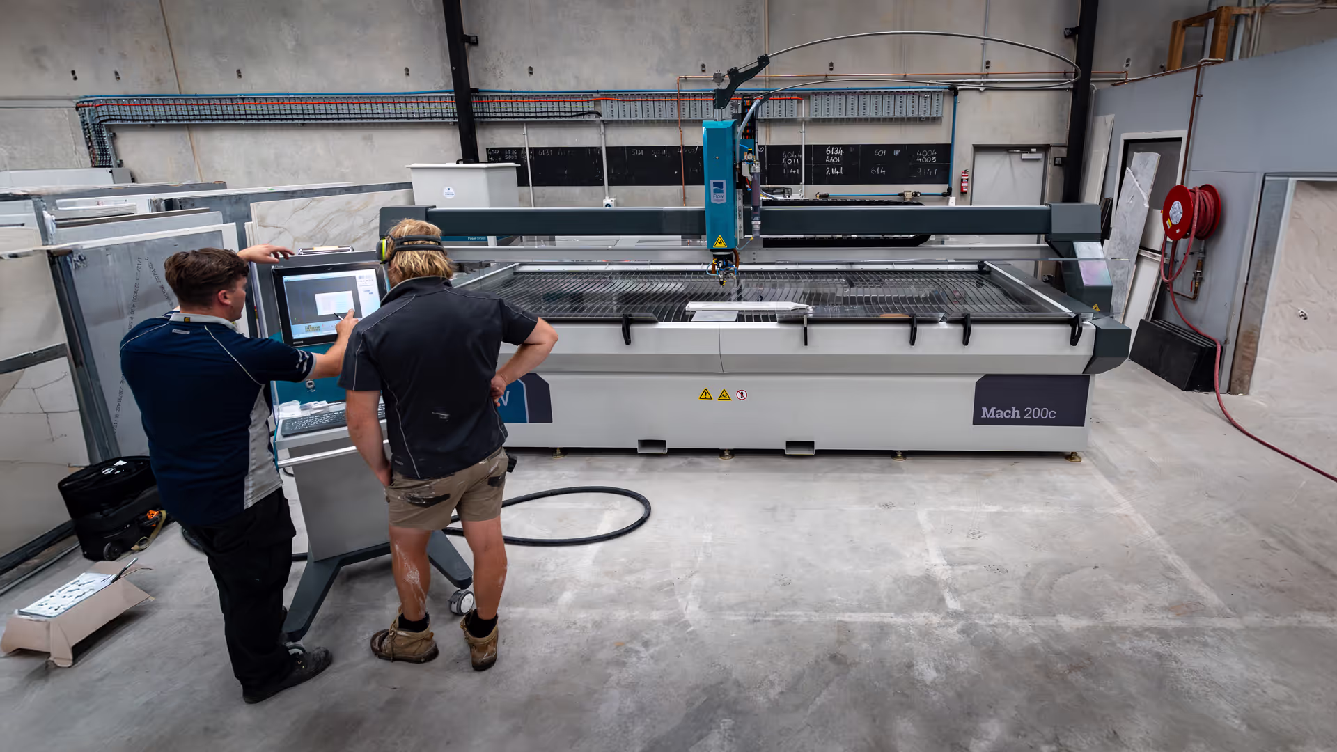 over the shoulder view of a man being trained on a waterjet cutter