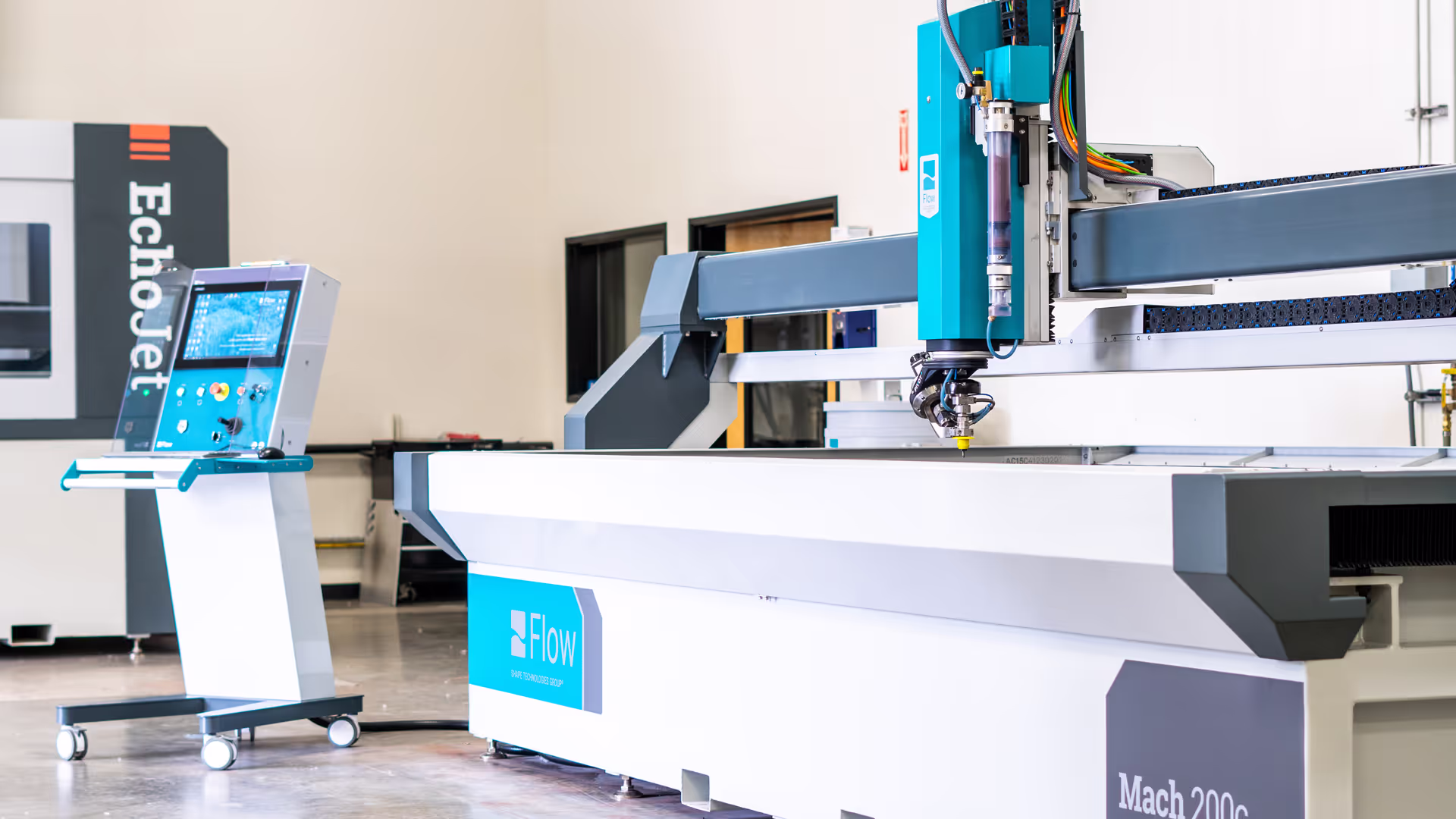 Operator using the Mach 200c waterjet cutting machine in a workshop.