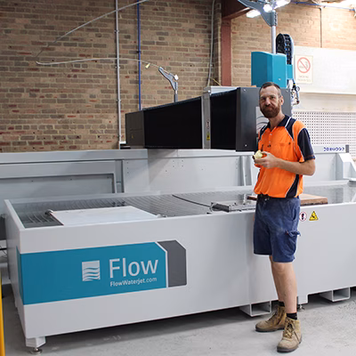 A happy customer in front of a newly installed water jet cutter machine Mach 200 flow water jet