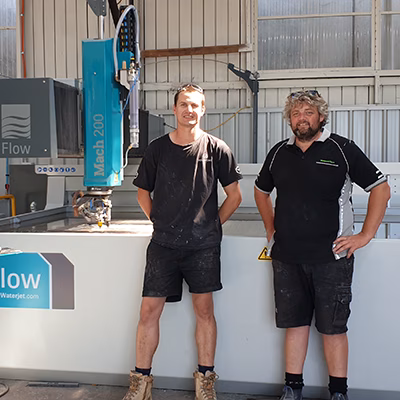 Two men standing in front of a 4 m Mac 200 flow Water jet cutting machine