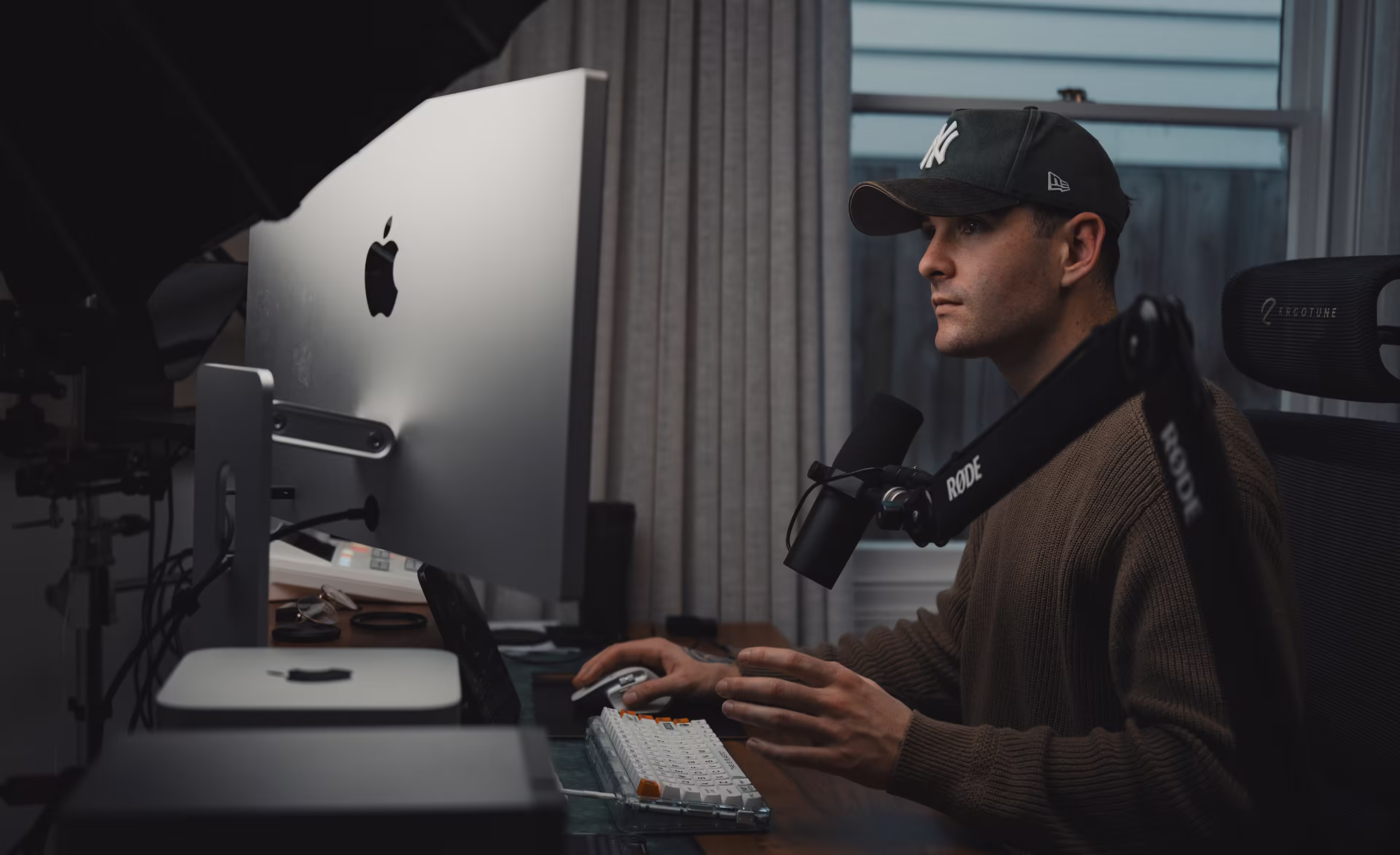 a man sitting at a desk with a microphone and a computer
