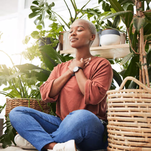 Yoga Basics - Femme méditant en pleine nature, assise en tailleur parmi des plantes vertes, profitant d’un moment de bien-être et de relaxation.