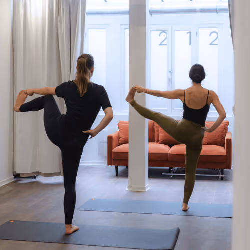 Deux participantes en équilibre sur une jambe pendant un cours au studio Yoze Arts et Métiers 2.