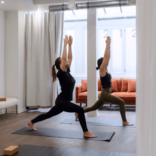Deux participantes en posture de fente, les bras levés, au studio Yoze Arts et Métiers 2.