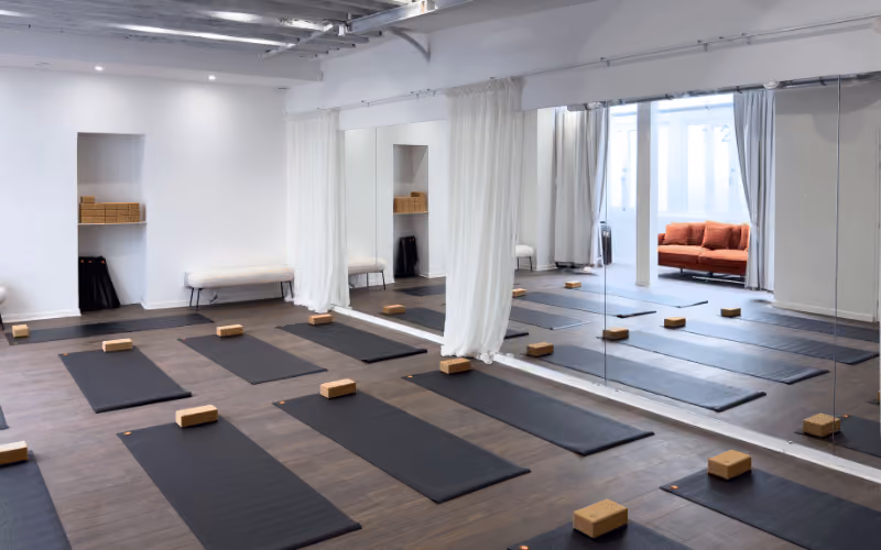 Salle du studio Yoze Arts et Métiers 2 avec tapis noirs, blocs de yoga et grands miroirs.
