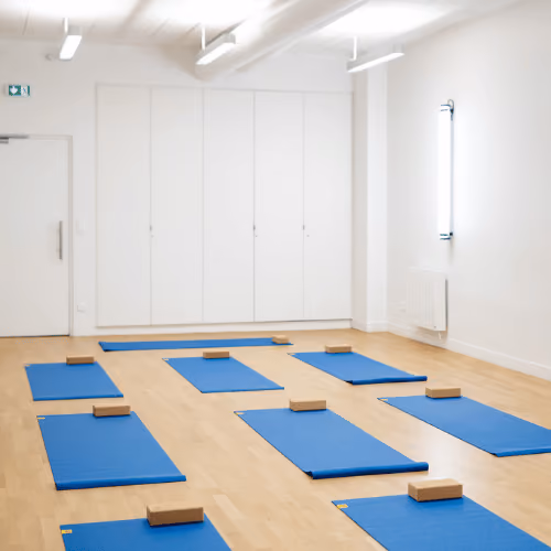 Studio Yoze Cadet – Cromot : vue de la salle blanche avec tapis bleus et briques de yoga.