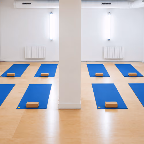 Studio Yoze Cadet – Cromot : rangées de tapis bleus et briques autour d’un poteau blanc.