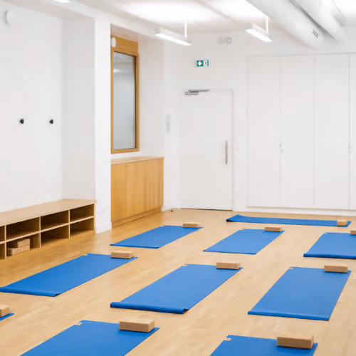 Studio Yoze Cadet – Cromot : tapis bleus et briques sur un parquet, avec rangements bas et murs blancs.
