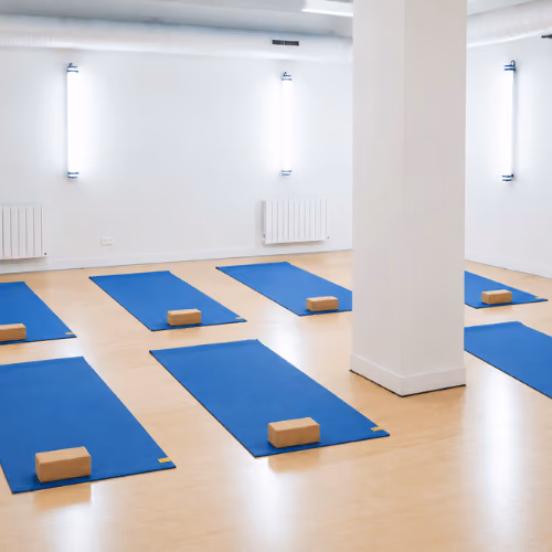 Studio Yoze Cadet – Cromot : tapis bleus et briques dans une salle blanche éclairée par des appliques murales.