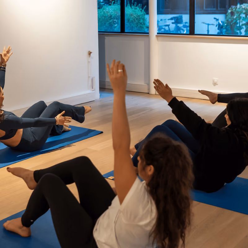 Cours collectif au studio Charonne – Atelier 77 : participants en équilibre assis sur leurs tapis