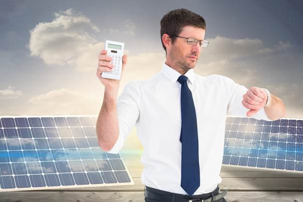 Mann mit Rechner in der Hand, der auf die Uhr schaut mit Solaranlagen im Hintergrund.